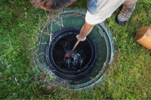 A person reaching into a septic tank.