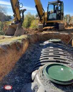 Large Digger Next to a Partially Covered Black and Green Septic Tank.