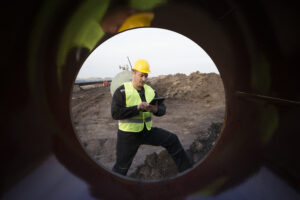 a person in a yellow helmet and vest looking at a tablet