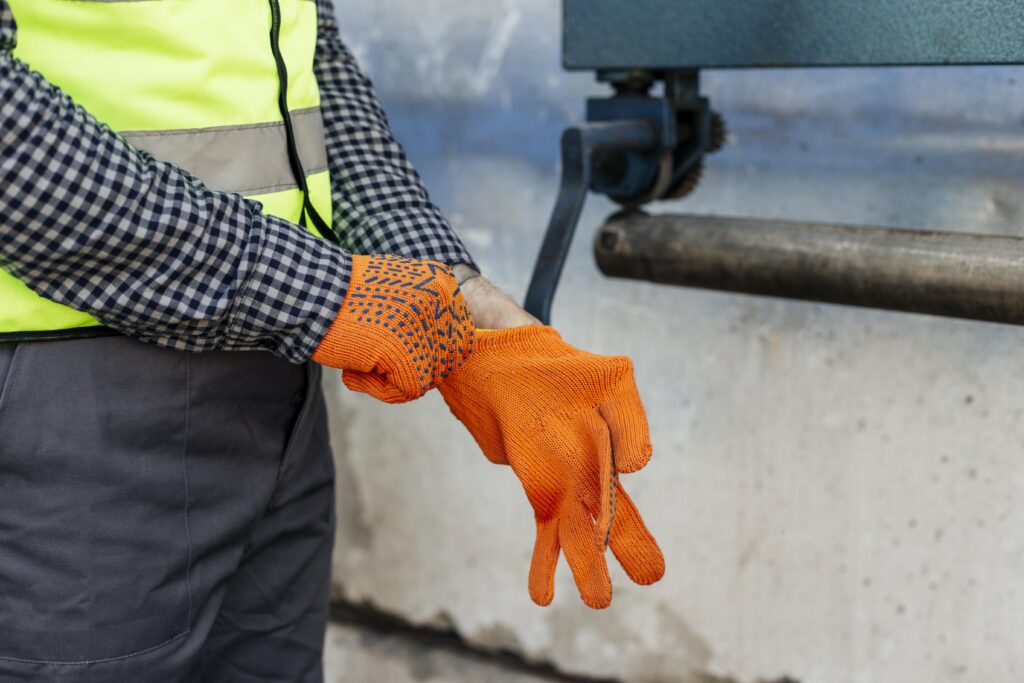 Worker putting on orange gloves