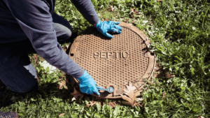 A worker wearing rubber gloves closes up the lid to a septic tank.