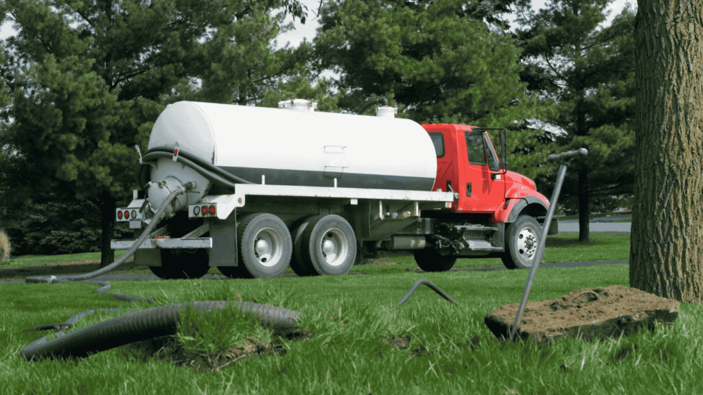 A septic truck pumps sludge from a nearby septic tank.