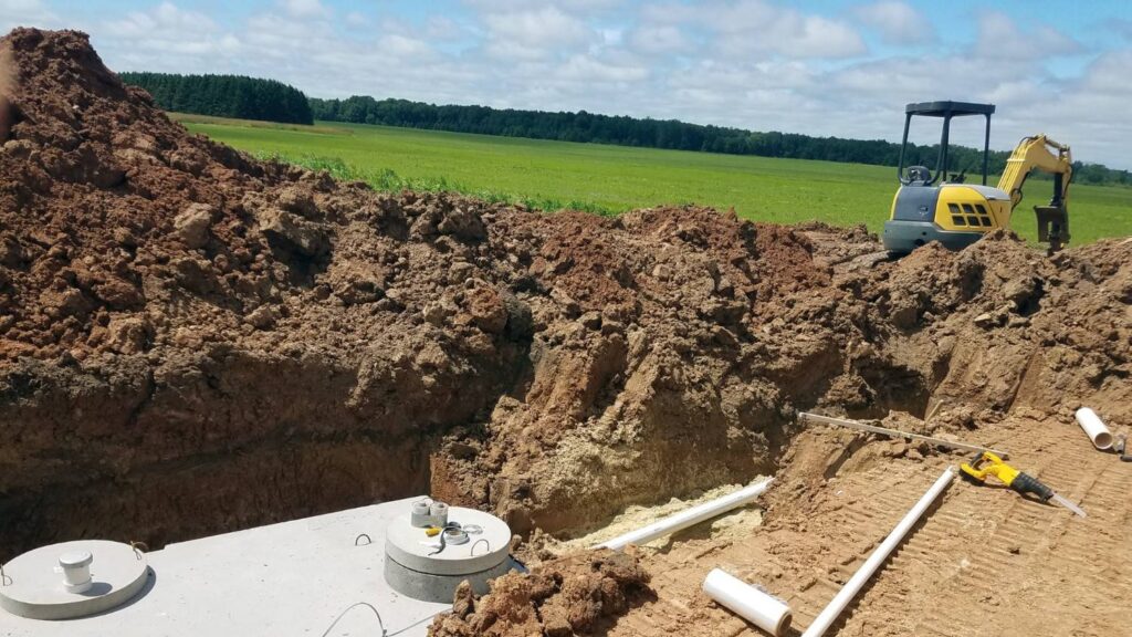A septic tank during installation next to a small excavator machine.