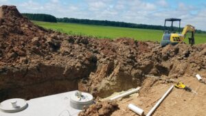 A septic tank during installation next to a small excavator machine.