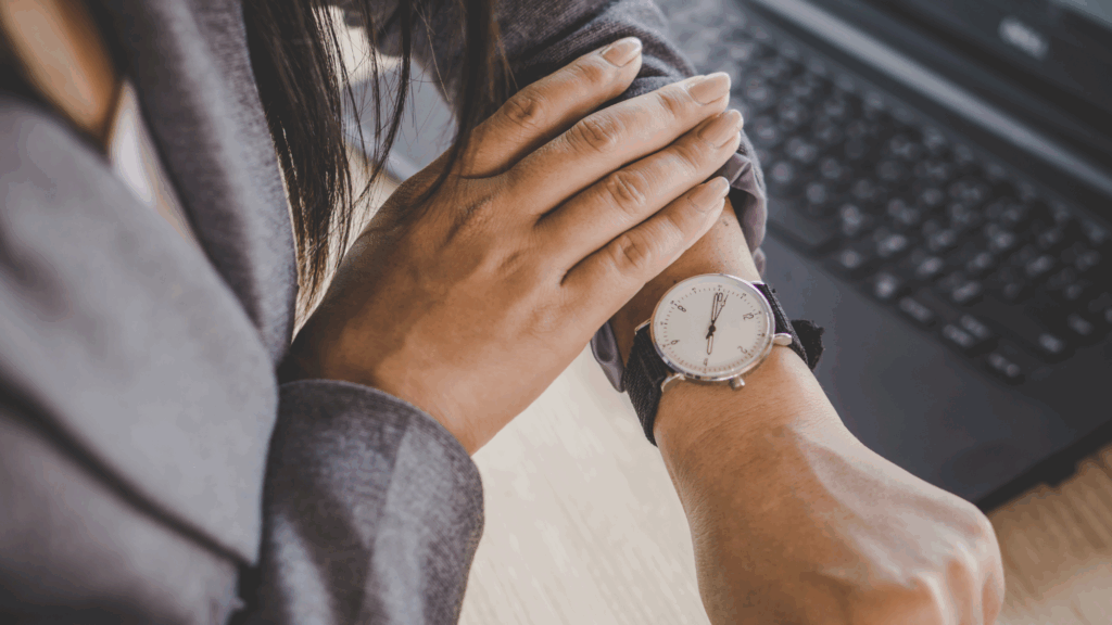 A woman wearing a grey blazer checks her wristwatch.