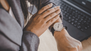 A woman wearing a grey blazer checks her wristwatch.